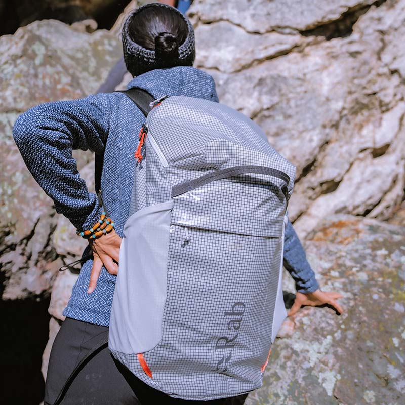 Woman wearing a Rab day hiking backpack at a rocky crag