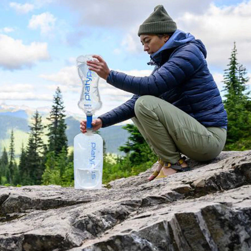 Person using Platypus water filter & bottle on a rock outdoors
