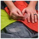 Applying a small silnylon patch to a red drybag by hand