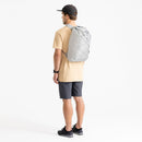 man wearing a grey sea to summit light backpack on a white background