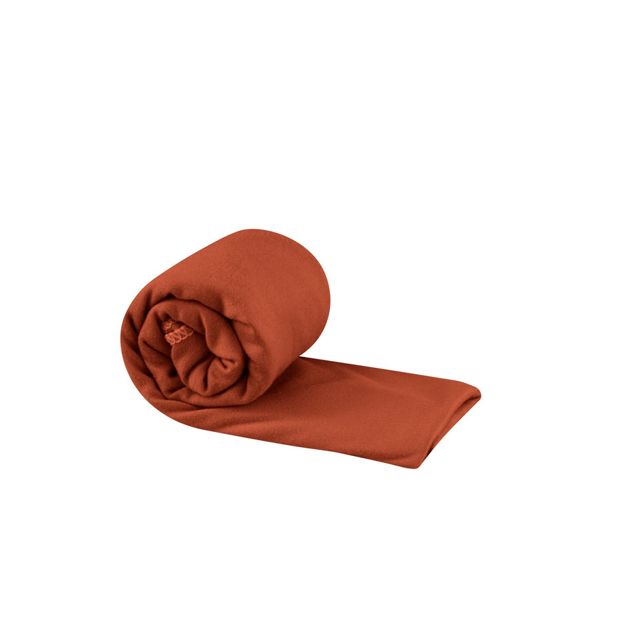 A rust-colored, lightweight Sea to Summit Pocket Towel rolled into a compact cylinder.
