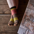 A woman wearing Darn Tough Womens Heady Betty Micro Crew Lightweight Hiking Socks sits on a wooden floor by a topographic map, ready for her next hike with comfort and performance from these trail socks.
