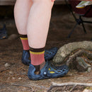 A person stands outdoors on dirt and rocks, ready for adventure in Darn Tough Womens Heady Betty Micro Crew Lightweight Hiking Socks with yellow stripes and blue perforated slip-on shoes.
