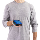 A person in a light gray long-sleeve shirt holds a small blue and black electronic device in their right hand at stomach height against a plain white background, with a Sea to Summit Folding Bucket (10L) resting nearby.