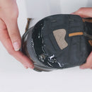 Close-up of a person holding a black sandal with a white background
