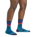 A woman models Darn Tough Womens Mirnavated Micro Crew Ultra-Lightweight Running Socks, featuring an abstract blue, teal, purple, and orange pattern. Only her legs and feet are shown against a white background.