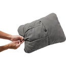 Person opening a gray compression bag on a white background