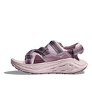 The Hoka Womens Infini Hike TC Trail Sandal, in mauve and light pink, features a thick cushioned sole, adjustable straps, and rugged tread for comfort and outdoor use. Shown in side profile on a white background.