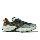 The Mens Speedgoat 7 Trail Running Shoe by Hoka features a thick cushioned sole, bold branding, green/black/orange/white colors, mesh and synthetic upper, and a durable Vibram outsole for superior traction.