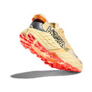 The Womens Speedgoat 7 Trail Running Shoe by Hoka is shown in beige and orange, angled upward to display its thick, textured sole with bright red treads and the Hoka logo on the side, casting a shadow on a white background.