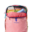 A Cotopaxi Allpa 28L Travel Pack - Del Día in pink sits with its top unzipped, displaying a folded blue item, a mesh pocket, and a white checkered rectangular object inside. This sustainably made backpack combines vibrant style and practical features for any adventure.
