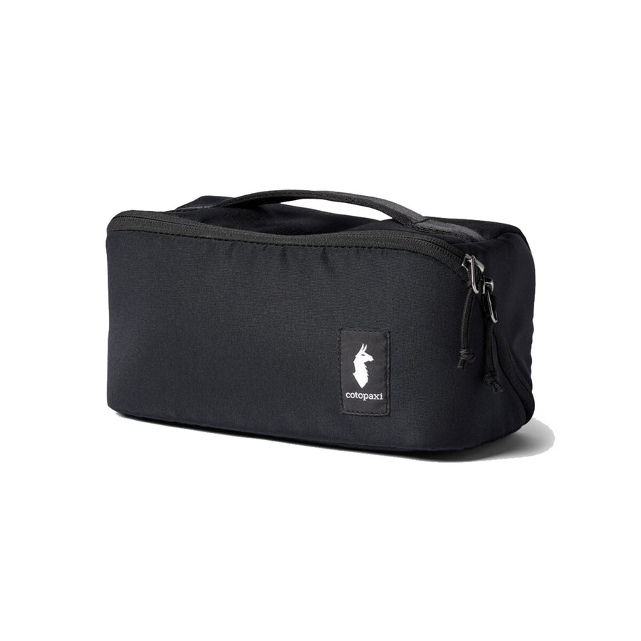 A black rectangular Cotopaxi Viaje Toiletry Kit - Cada Día, crafted from recycled fabric, features a top handle, zipper closure, and a distinctive Cotopaxi logo patch on the front—perfect for organizing your travel essentials.