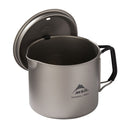 The MSR Titan Kettle 900mL is an ultralight titanium camping pot, featuring a lid with a black handle and the MSR logo displayed on the side. Ideal for backpacking cookware, the lid is pictured leaning against the pot for easy access.