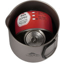 A red MSR IsoPro fuel canister and a metal stove are neatly packed inside the gray MSR Titan Kettle 900mL with a foldable handle, showcasing the efficiency of quality backpacking cookware.