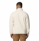A man is shown from the back wearing a cream Mens Helvetia Half Snap Fleece by Columbia and light brown cargo pants, standing against a plain white background.