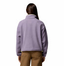 A woman with long brown hair, seen from behind, wears the Columbia Womens Helvetia II Cropped Sherpa Half Snap Fleece in light purple and brown pants against a plain white background.