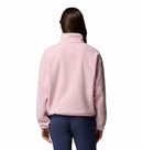 A person with long brown hair, seen from behind, wears the Columbia Womens Helvetia II Cropped Sherpa Half Snap Fleece in light pink and dark pants against a plain white background.