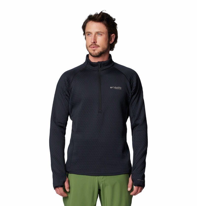 A man in a black Columbia Mens Crystal Leaf Omni-Heat Helix Technical Half Zip Fleece and green pants stands facing forward against a white background.