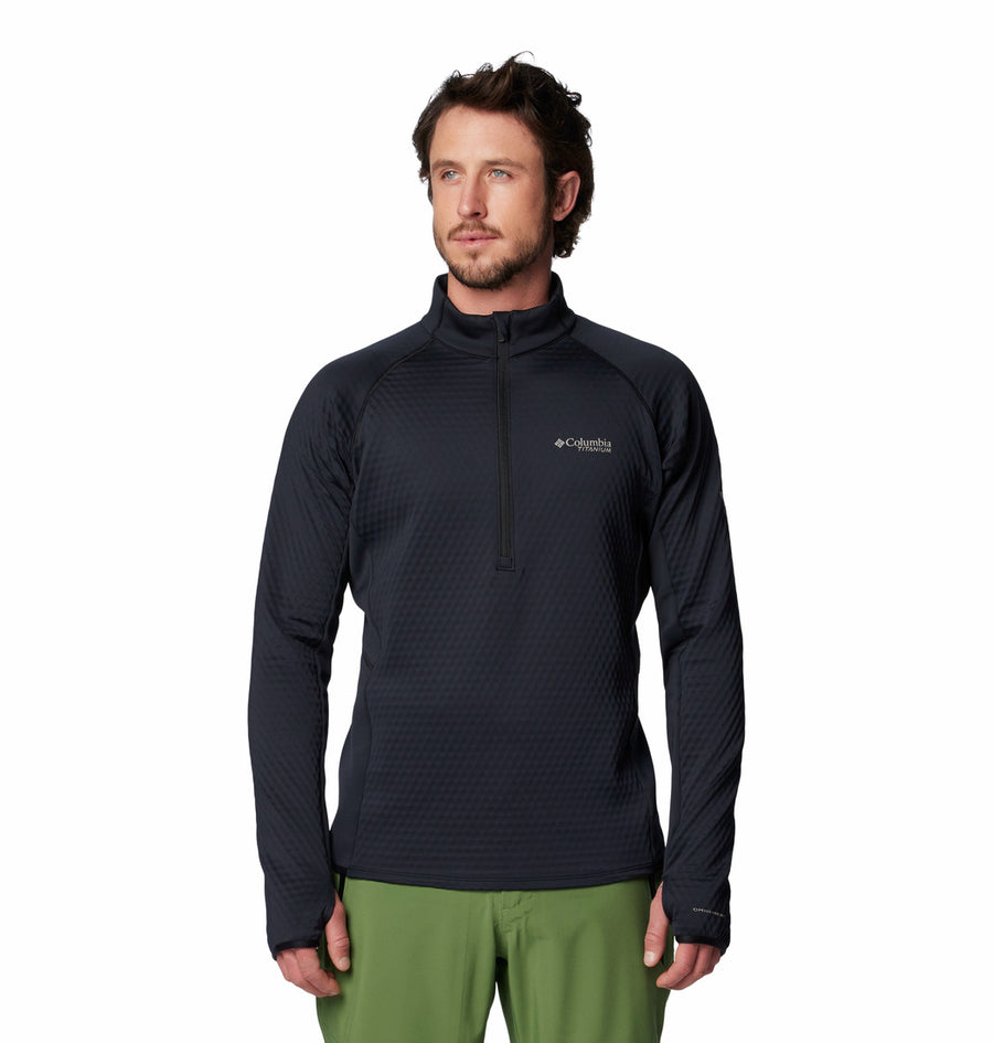 A man in a black Columbia Mens Crystal Leaf Omni-Heat Helix Technical Half Zip Fleece and green pants stands facing forward against a white background.