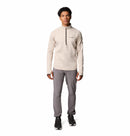 A man faces forward wearing a Columbia Mens Crystal Leaf Omni-Heat Helix Technical Half Zip Fleece in light beige, gray pants, and black sneakers against a plain white background.