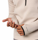 A man in a light beige Columbia Mens Crystal Leaf Omni-Heat Helix Technical Half Zip Fleece with thumbholes adjusts the sleeve, showcasing Omni-Heat near the wrist and emphasizing its performance midlayer design.