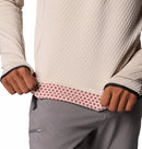 A person pulls up a Columbia Mens Crystal Leaf Omni-Heat Helix Technical Half Zip Fleece, revealing a pink and red polka-dot inner lining; only their torso and hands are visible.