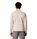 A person with short curly hair, seen from behind against a white background, wears a light beige Columbia Mens Crystal Leaf Omni-Heat Helix Technical Half Zip Fleece with textured sleeves and back, paired with gray pants.