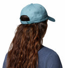 Person with long, wavy brown hair wearing a light blue Columbia Provisions Ball Cap and a blue shirt, shown from behind against a white background. The Columbia Provisions Ball Cap features an adjustable back closure for a comfortable fit.