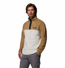 A man wears the Columbia Mens Steens Mountain™ II Half Snap Fleece in tan and white with a button-up collar and gray pants, standing against a white background—PFAS-free, perfect for everyday wear.