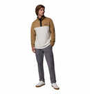A man stands against a white background in the Columbia Mens Steens Mountain™ II Half Snap Fleece, gray cargo pants, and white sneakers, with one hand in his pocket, channeling relaxed everyday style.