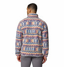 A man with short dark hair and gray pants faces away, wearing the Columbia Mens Helvetia II Printed Half Snap Fleece featuring colorful geometric and zigzag patterns in pastel blue, orange, yellow, purple, and pink.