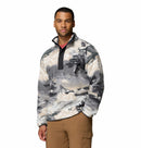 A man wears the Columbia Mens Helvetia II Printed Half Snap Fleece featuring a black snap collar and chest pocket, standing with one hand in his tan pants pocket against a plain white background.