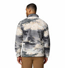 A man faces away, wearing the Columbia Mens Helvetia II Printed Half Snap Fleece with a gray, cream, and black cloud-like pattern and light brown cargo pants against a plain white background.