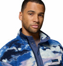 A man with short hair and a trimmed beard wears the Columbia Mens Helvetia II Printed Half Snap Fleece, featuring a blue and white pattern and high collar, standing against a plain white background.