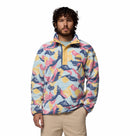 A man with curly hair and a beard wears the Columbia Mens Helvetia II Printed Half Snap Fleece with a high collar and khaki pants, standing against a plain white background.