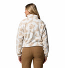 A woman with long blonde hair, seen from the back, wears the Columbia Womens Helvetia II Cropped Sherpa Half Snap Printed Fleece in beige and white with tan pants against a plain white background.