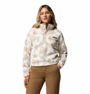 A woman wearing the Columbia Womens Helvetia II Cropped Sherpa Half Snap Printed Fleece stands with one hand in her pocket against a plain white background.