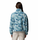 A woman with long brown hair is seen from the back against a plain white background wearing Columbia’s Womens Helvetia II Cropped Sherpa Half Snap Printed Fleece in blue and white print, paired with light-colored pants.