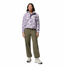 A woman faces forward, wearing the Columbia Womens Helvetia II Cropped Sherpa Half Snap Printed Fleece in light purple, olive green pants, and white sneakers against a plain white background.