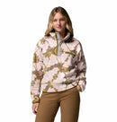 A woman wears the Columbia Womens Helvetia II Cropped Sherpa Half Snap Printed Fleece with brown pants, standing with one hand in her pocket against a white background.