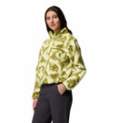 A woman stands with one hand in her pocket, wearing the Columbia Womens Helvetia II Cropped Sherpa Half Snap Printed Fleece and dark gray pants, against a white background.
