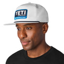 Man wearing a white cap with YETI Coolers logo on a white background