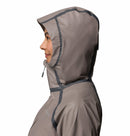 A woman in profile wears the Columbia Womens Reign No Shine Waterproof Jacket, light brown with black seam details, against a white background, highlighting its reliable rain protection.
