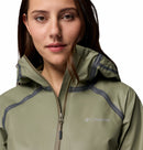 A woman in the Columbia Womens Reign No Shine Waterproof Jacket, featuring a hood and olive green color, poses against a white background for dependable rain protection.