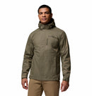 A man faces forward, wearing an olive green Columbia Mens Pouring Adventure™ III Waterproof Hiking Jacket and light brown pants, set against a plain white background.