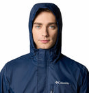 A man wearing the Columbia Mens Pouring Adventure™ III Waterproof Hiking Jacket in blue, hood up, faces forward against a white background.