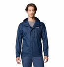 A man wears a Columbia Mens Pouring Adventure™ III Waterproof Hiking Jacket in blue over a gray shirt, standing facing forward against a plain white background.