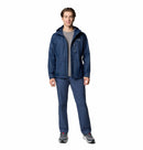 A person stands smiling against a white background, wearing the Columbia Mens Pouring Adventure™ III Waterproof Hiking Jacket in navy blue, matching pants, a gray t-shirt, and gray sneakers with white soles.
