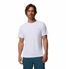 A man with wavy brown hair wears the Columbia Mens Zero Rules™ Light Technical T-Shirt in plain white, featuring moisture-wicking fabric and a small left-chest logo, paired with teal pants against a white background.