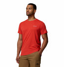 A man wears a Columbia Mens Zero Rules™ Light Technical T-Shirt in bright red and tan cargo shorts, standing with one hand in his pocket against a plain white background.